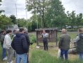 Personen stehen auf einer Wiese, eine Person hält ein Plakat in der Hand