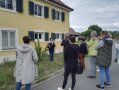 Personen stehen im Halbkreis vor einem Gebäude