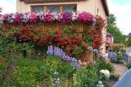 Haus mit Garten und Balkon, an dem Blumen angebracht sind