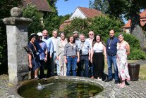 Personengruppe im Freien hinter einem steinernen Brunnen