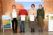 Vier Frauen stehen auf einer Bühne und präsentieren Urkunden.