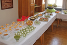 Schälchen mit Desserts und Häppchen auf Platten auf einem langen Tisch