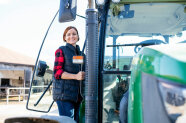 Junge Frau steigt in Traktor  